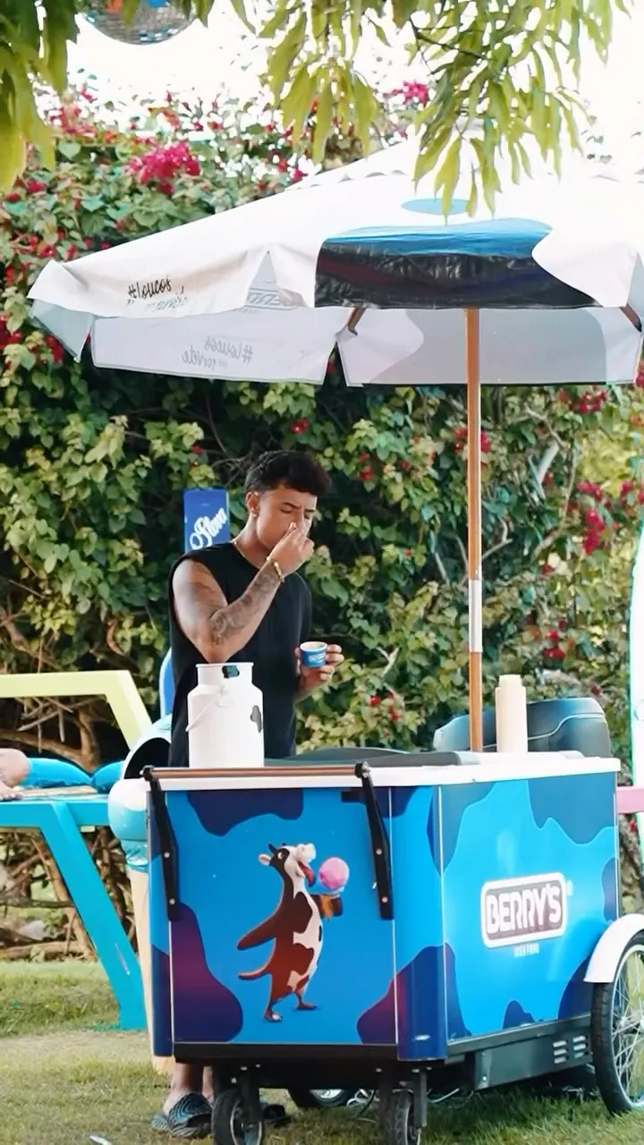 Carrinho de sorvete Berry's azul com guarda-sol, montado em um evento ao ar livre